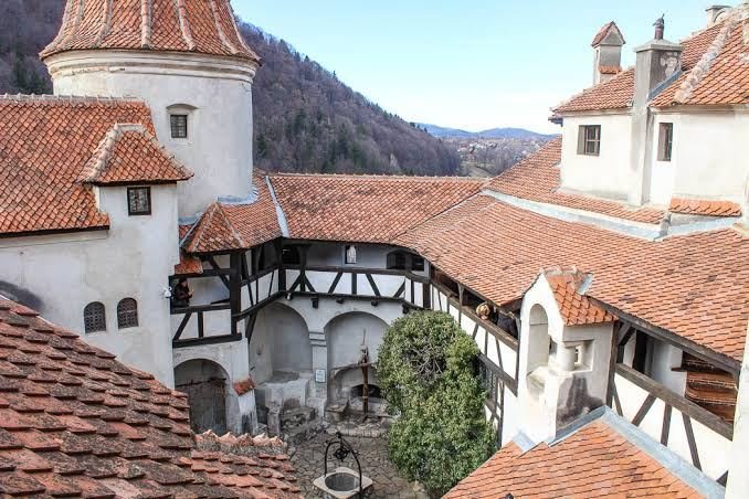 Inner courtyard of Bran Castle with half-timbered galleries, terracotta roofs and a stone well