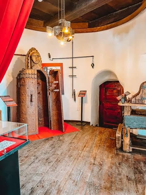 Museum room in Bran Castle displaying medieval torture devices and wooden artifacts