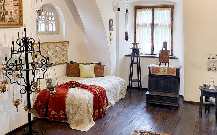 Furnished royal bedroom inside Bran Castle with embroidered bedspread and dark wooden floor