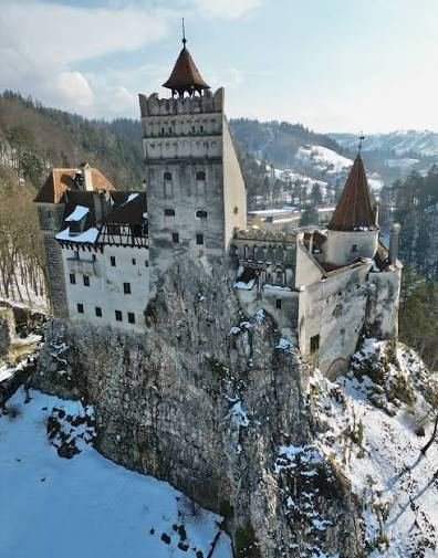 Bran Castle on its rocky cliff covered in snow in winter