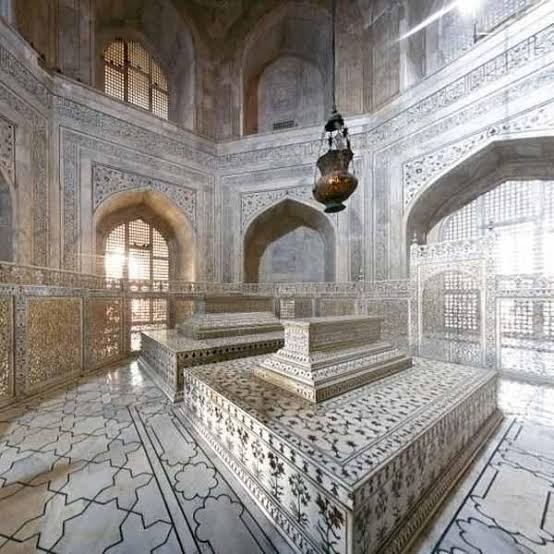 The cenotaphs of Mumtaz Mahal and Shah Jahan inside the Taj Mahal, surrounded by carved marble screens