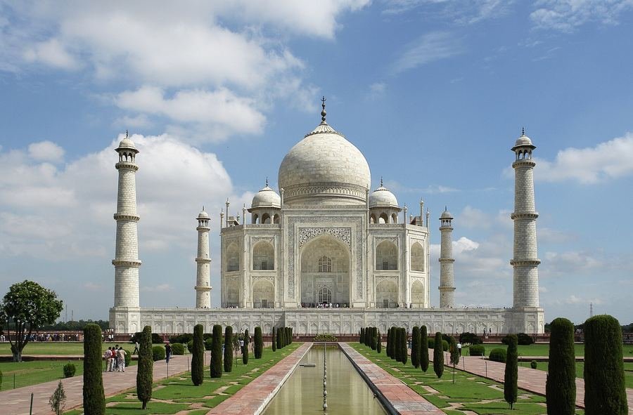 The Taj Mahal seen across its long reflecting pool and gardens under a blue sky