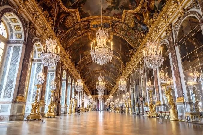 The Hall of Mirrors at Versailles with crystal chandeliers, mirrored arches and painted ceiling